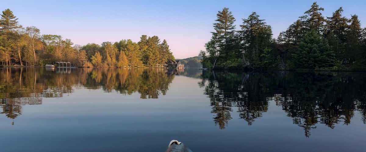 A calm lake with reflections of trees and a house.