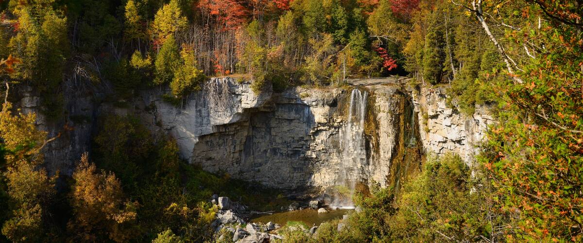 A waterfall cascading down a rocky cliff surrounded by autumn-colored trees.