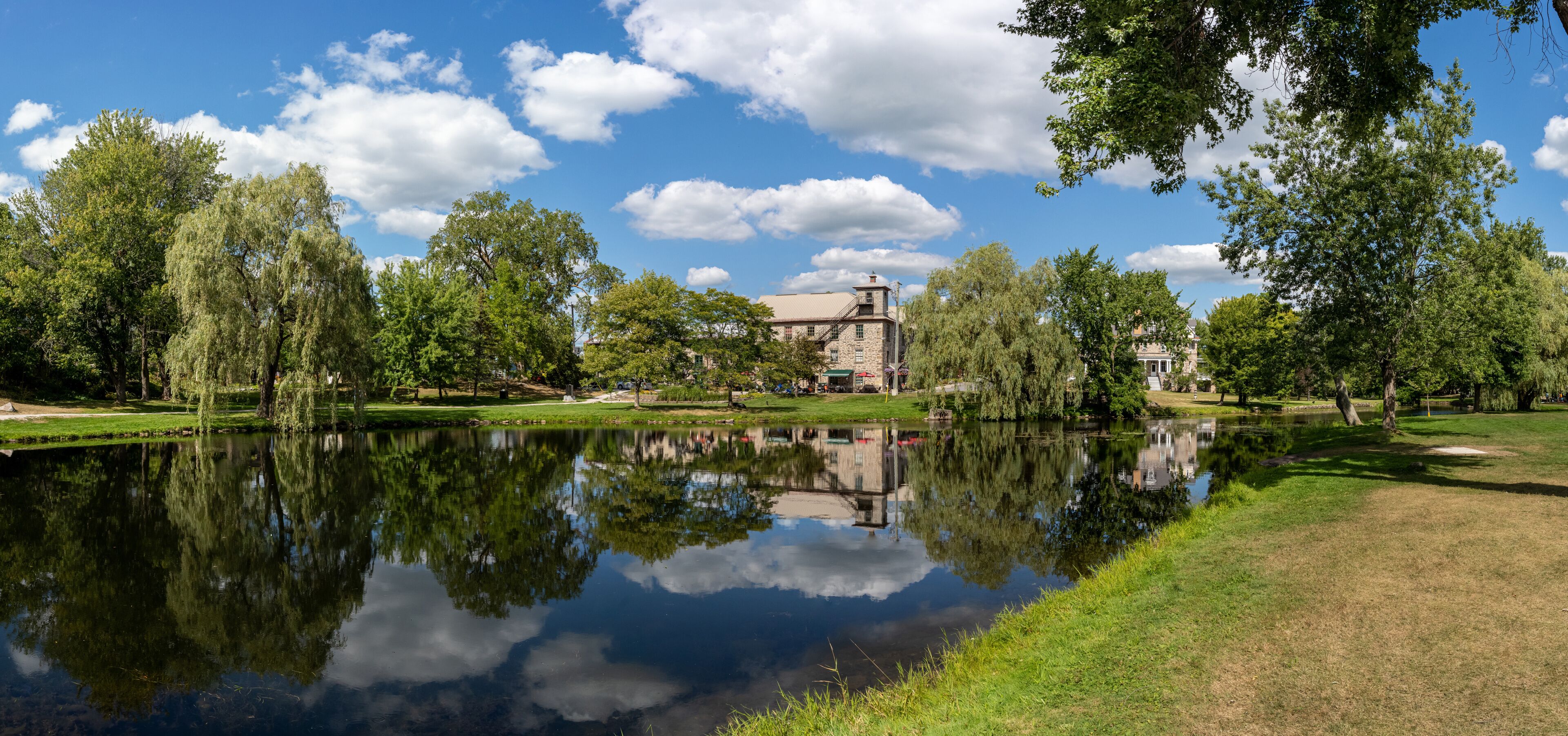 A serene lake with reflections of trees and a historic building in the background.