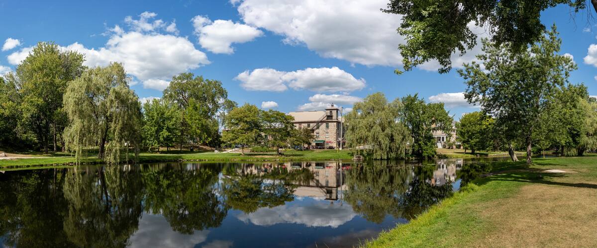 A serene lake with reflections of trees and a historic building in the background.