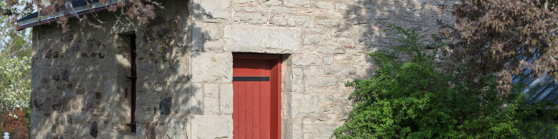 Historic 1892 stone jailhouse with a bright red door in Creemore, Ontario. Known as the smallest jail in North America, this little fieldstone lock-up is a famous heritage landmark.