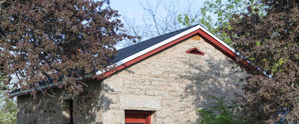 A stone building with a red door and a small triangular window.