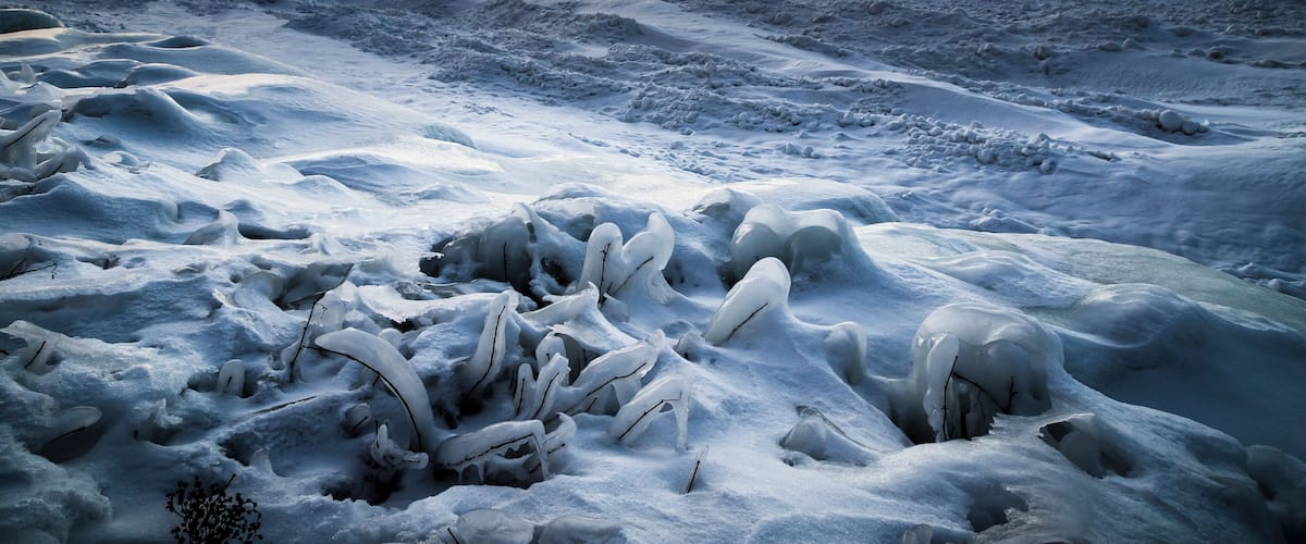 A frozen landscape with ice formations and a sunset in the background.