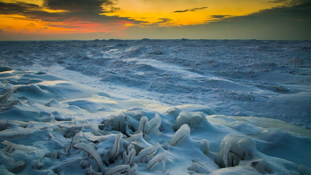 A frozen landscape with snow-covered terrain and ice formations.