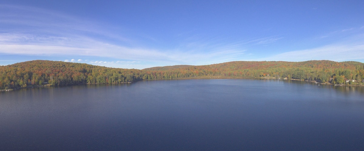 A calm lake surrounded by forested hills with autumn foliage.