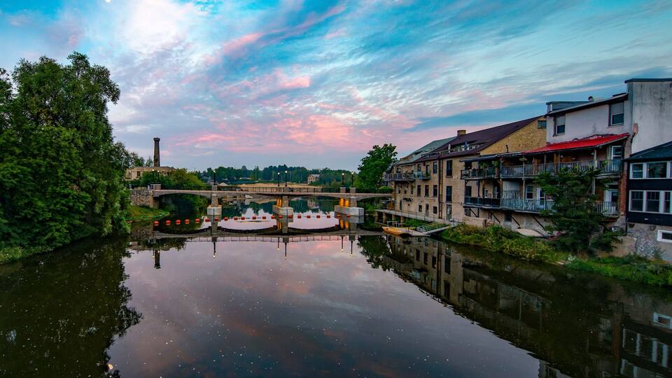 A river reflecting buildings and a bridge.