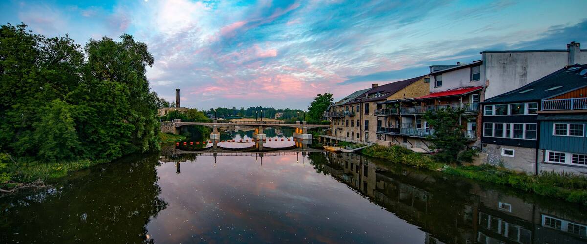 A river reflecting buildings and a bridge.