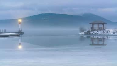Un llac congelat amb un far i una glorieta en una illa nevada.
