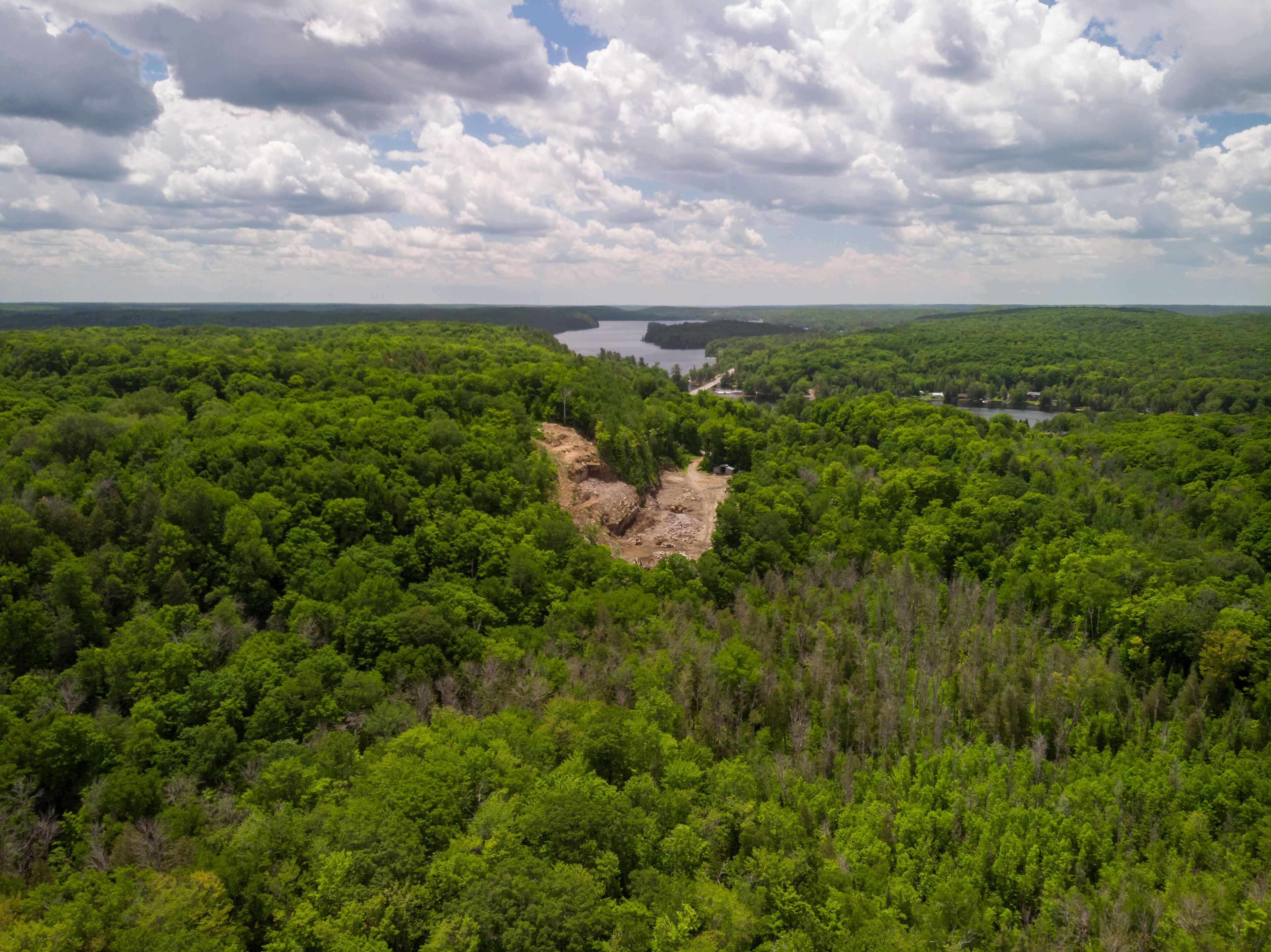 A small open-pit rock quarry has been carved out of a forested hillside.