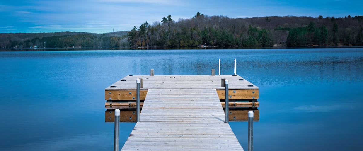 A wooden dock extending into a calm lake with a forested shoreline in the background.