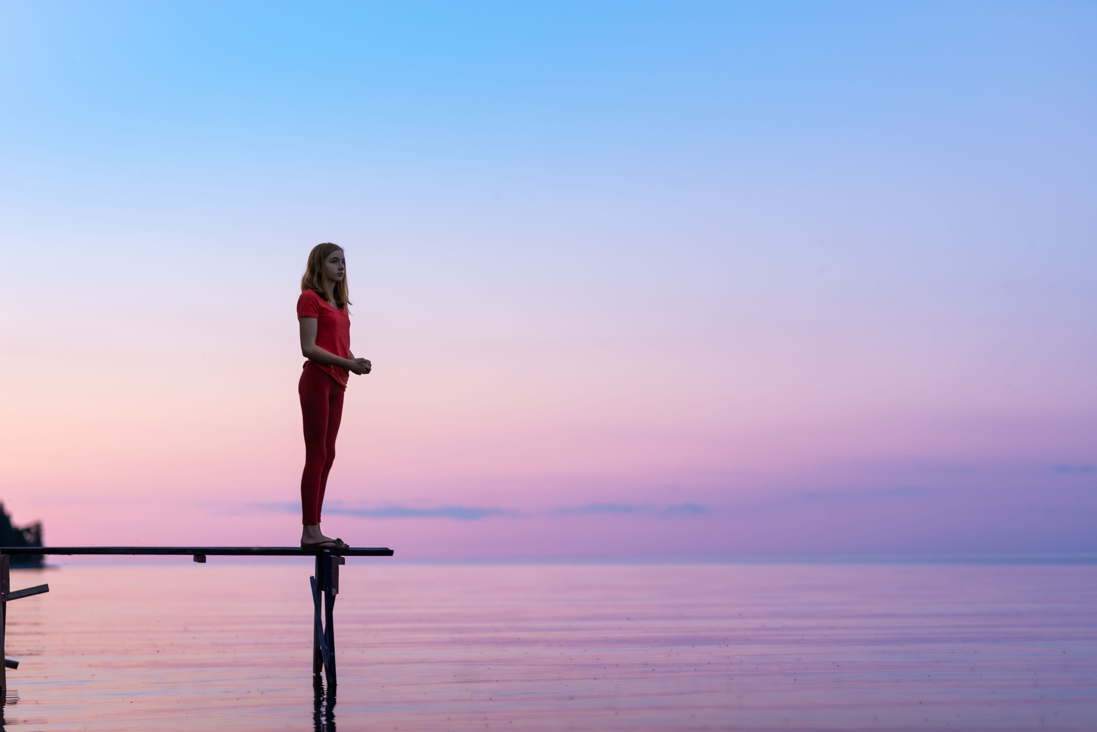 Teen Girl Looking Out at Dusk at Family Cottage on Dock at the Lake