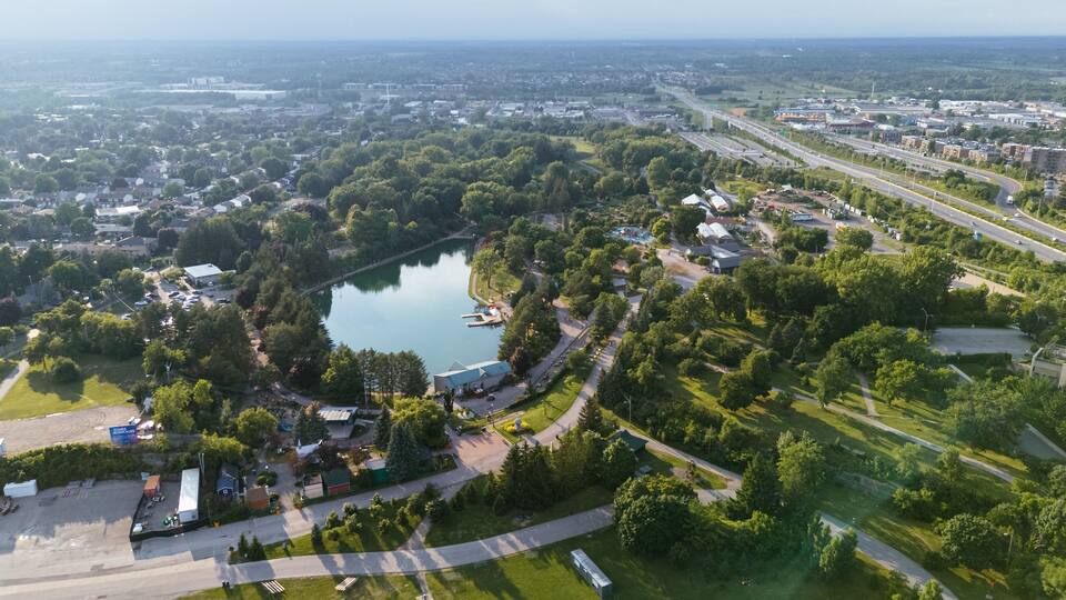 An aerial view of a town with a lake, roads, and surrounding greenery.