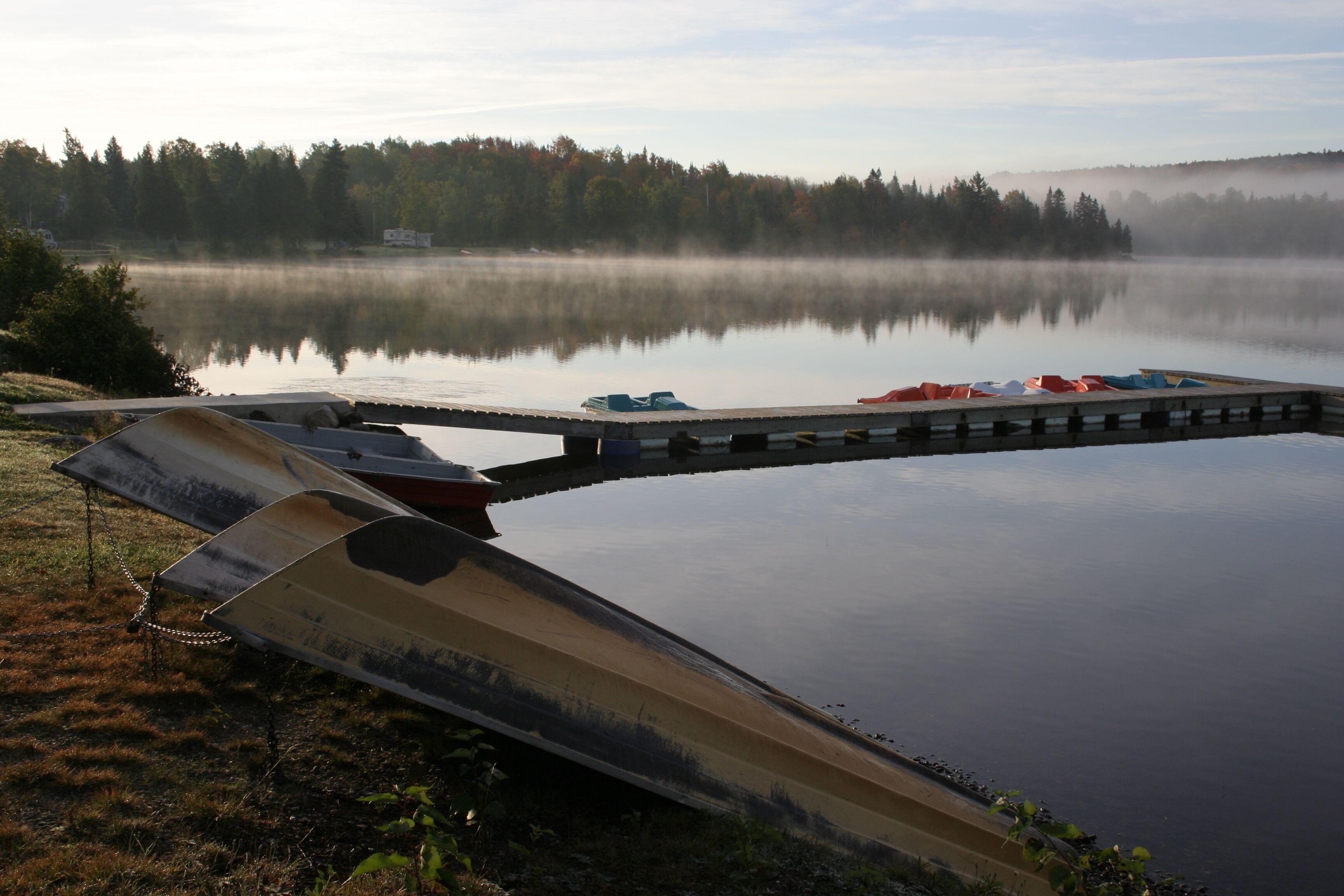 A calm lake with a wooden dock and a small boat.