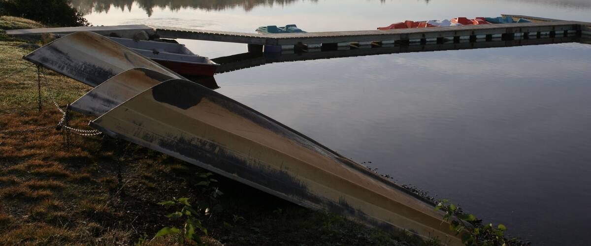 A calm lake with a wooden dock and a small boat.