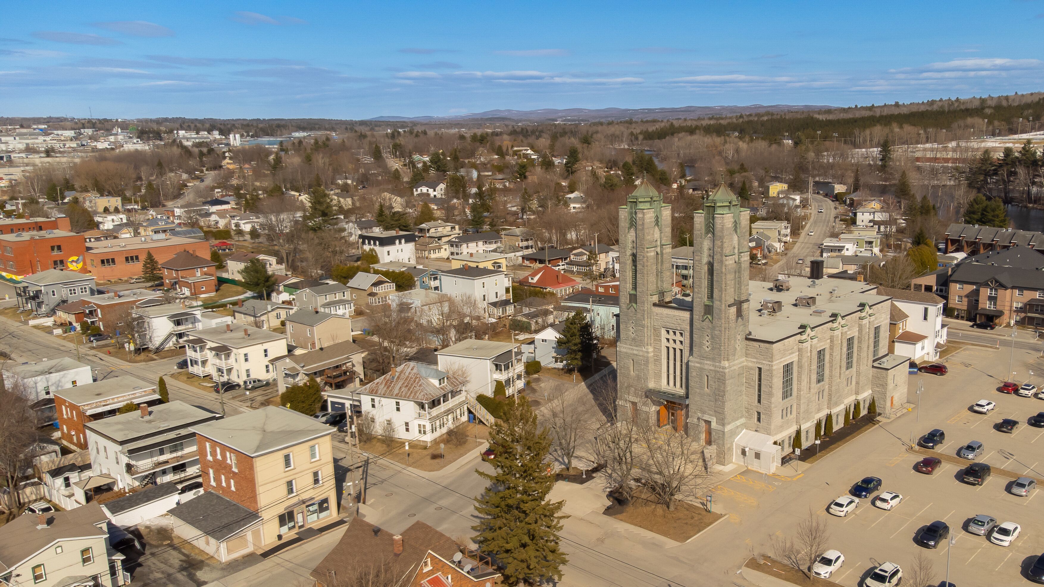 A town with a prominent church, residential houses, and a parking lot.
