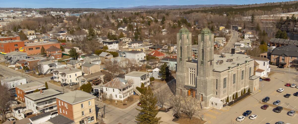 A town with a prominent church, residential houses, and a parking lot.