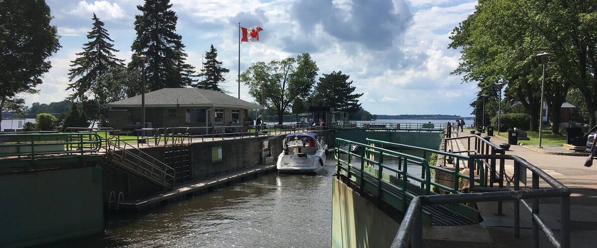 A canal with a boat, a Canadian flag, and a building in the background.