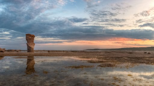 A coastal landscape with rock formations and a sunset.
