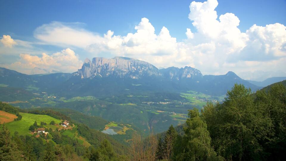 A mountain range with a prominent peak, lush green valleys, and scattered houses.