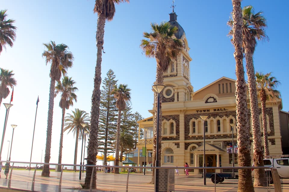 A town hall with a clock tower, surrounded by palm trees.