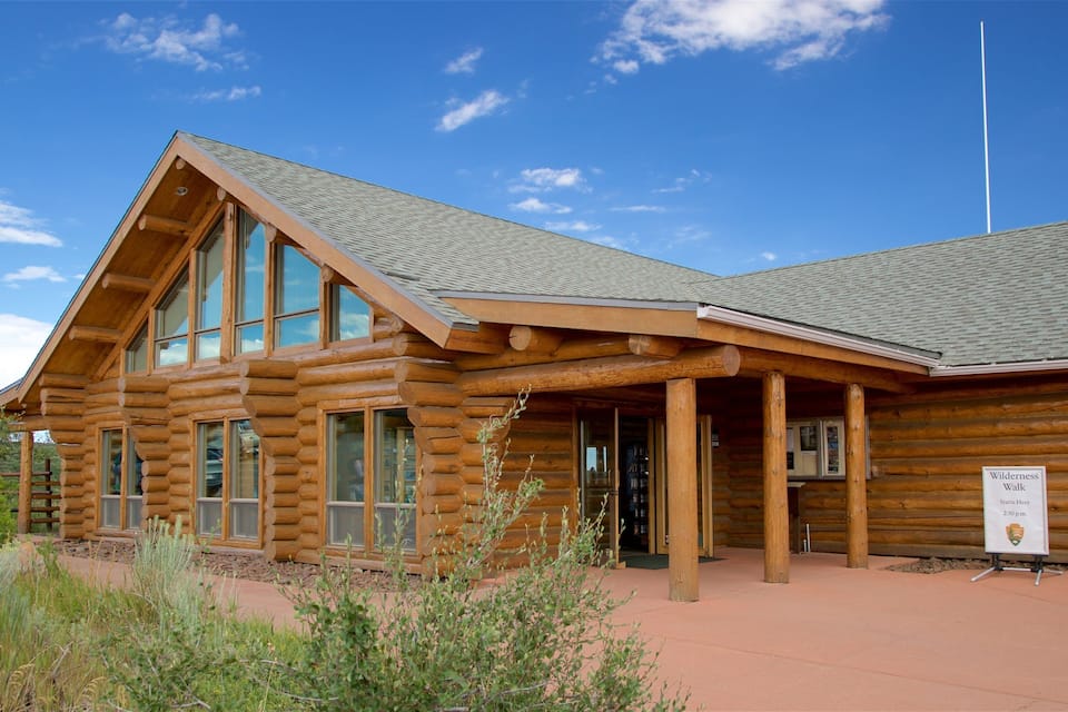 A wooden lodge with large windows and a sign indicating a wilderness walk starts here.