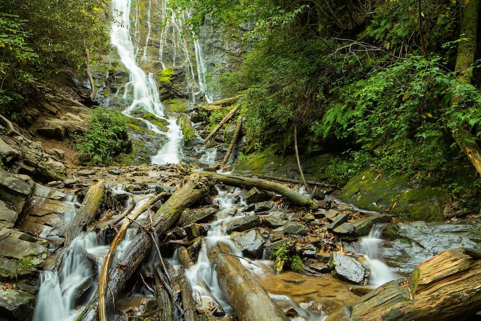 Een waterval die over rotsen stroomt in een bebost gebied.