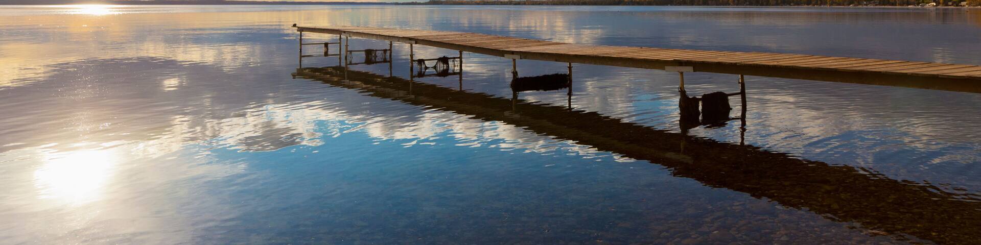 A Dock Leading Out Into The Lake At Sunrise; Pigeon Lake, Alberta, Canada