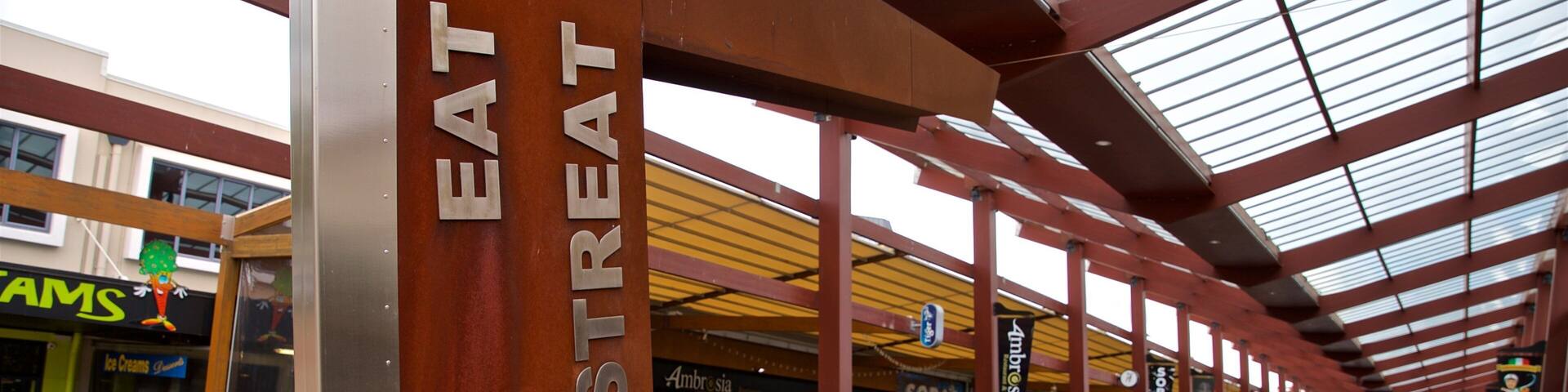 A covered pedestrian area with a prominent 'EAT STREAT' sign, outdoor seating, and various shops.