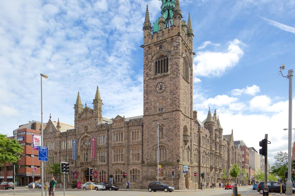 A historic building with a clock tower, surrounded by modern buildings and a busy street.