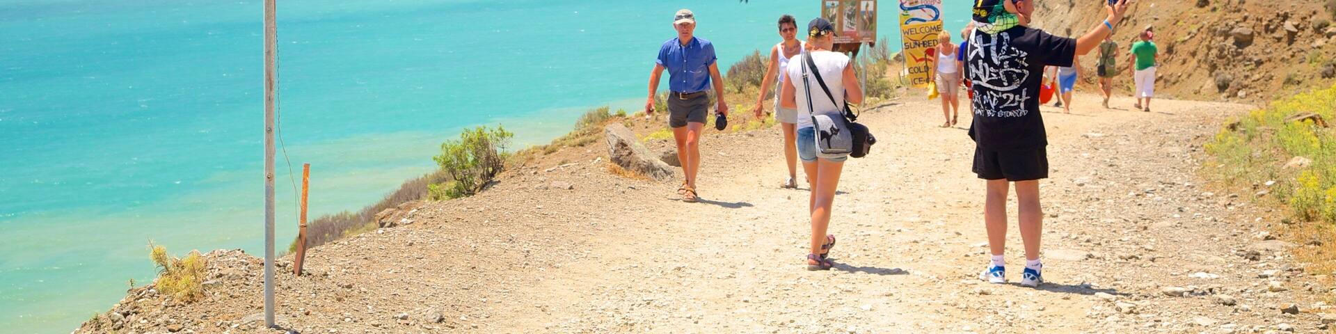 A coastal hiking trail with a sign reading "HOT WATER WELCOME".