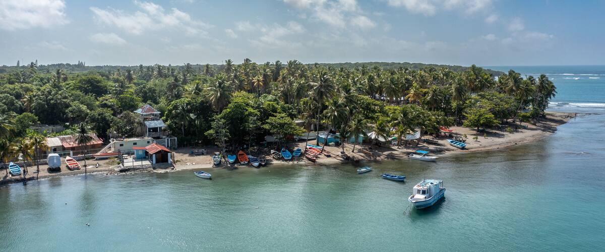 A tropical island with a beach, boats, and palm trees.
