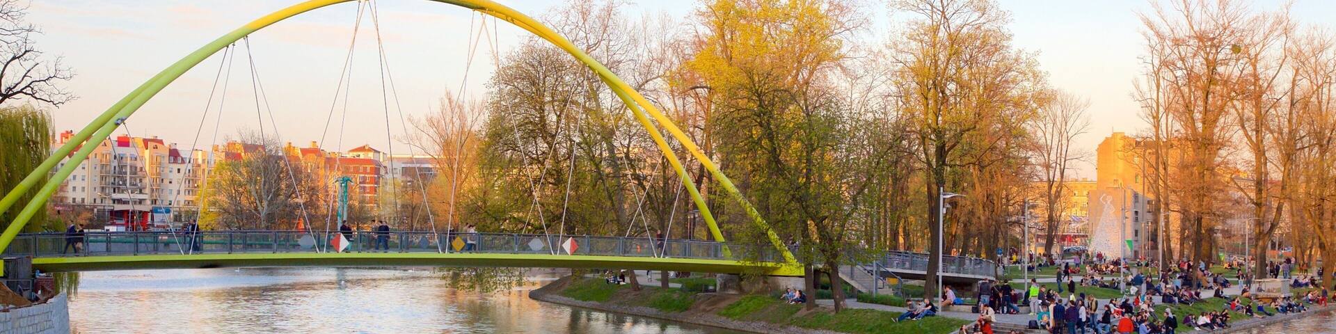 Un puente amarillo sobre un río, con gente sentada en la orilla.
