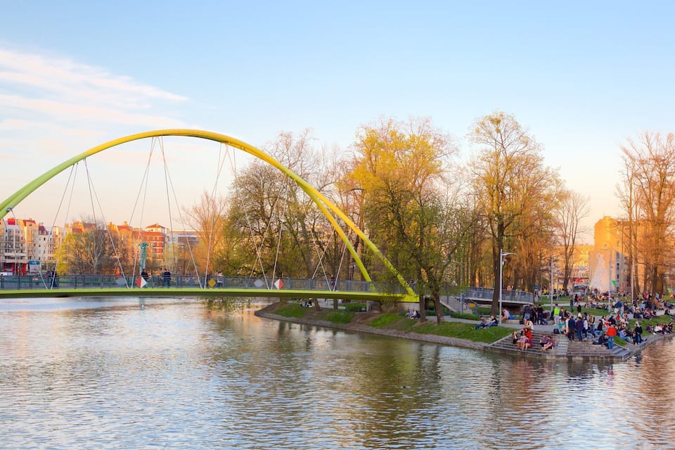 Un puente amarillo sobre un río, con gente sentada en la orilla.