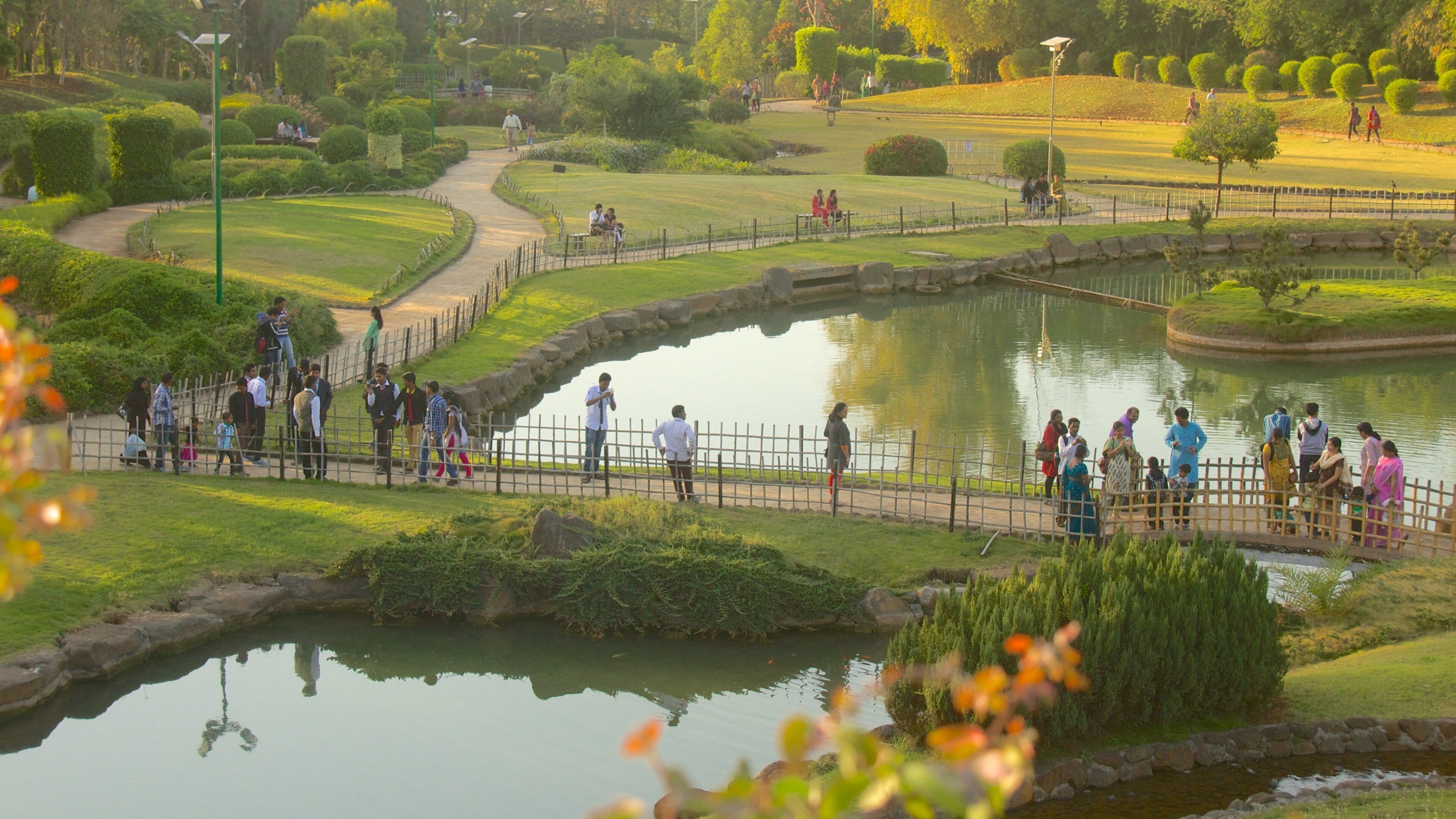 Pune featuring a lake or waterhole and a garden as well as a large group of people