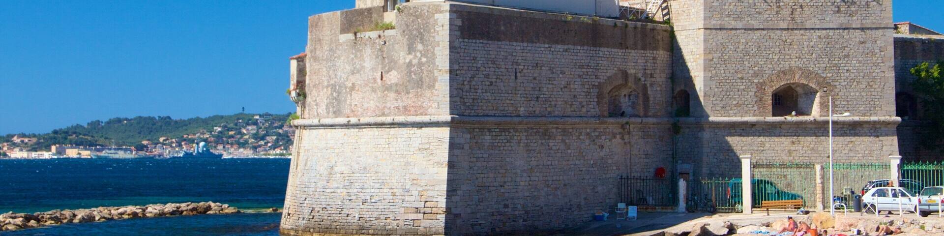 Una fortaleza de piedra histórica junto al mar, bajo un cielo azul despejado.