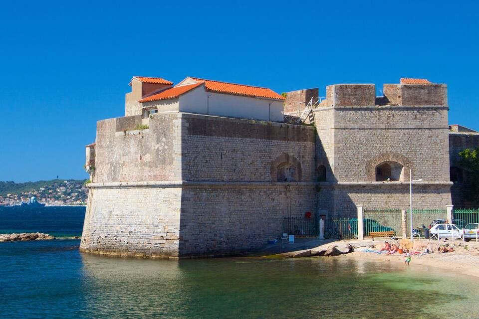A historic stone fortress by the sea with a clear blue sky.