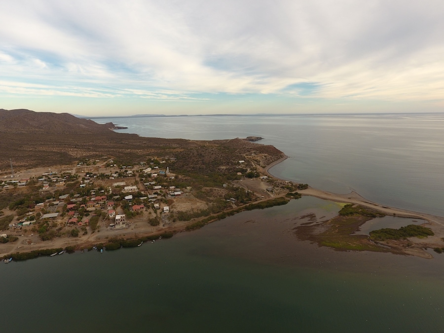 Ein Luftbild einer Küstenstadt mit Strand, Häusern und einem Bergpanorama.