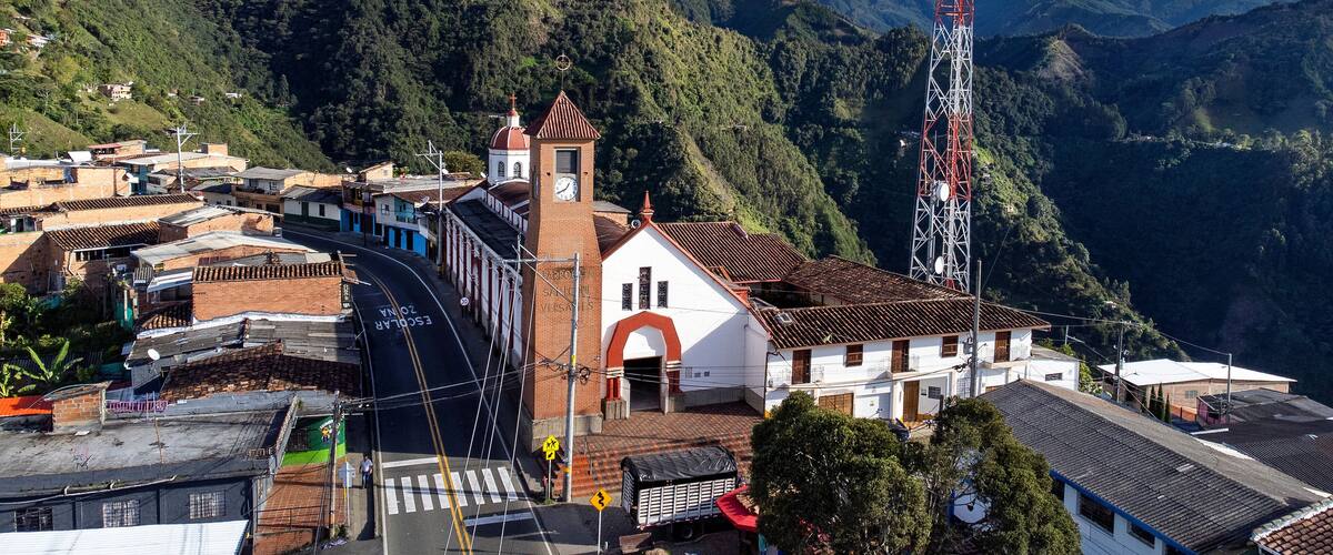 A mountainous town with a church, a winding road, and a cell tower.