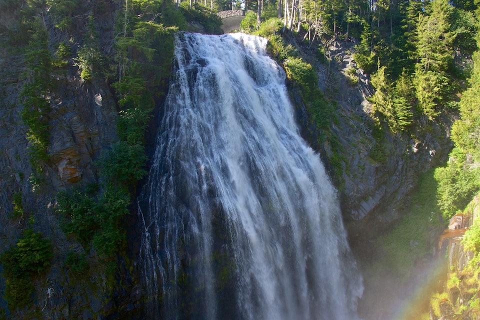 A waterfall cascading down a rocky cliff surrounded by dense green forest.