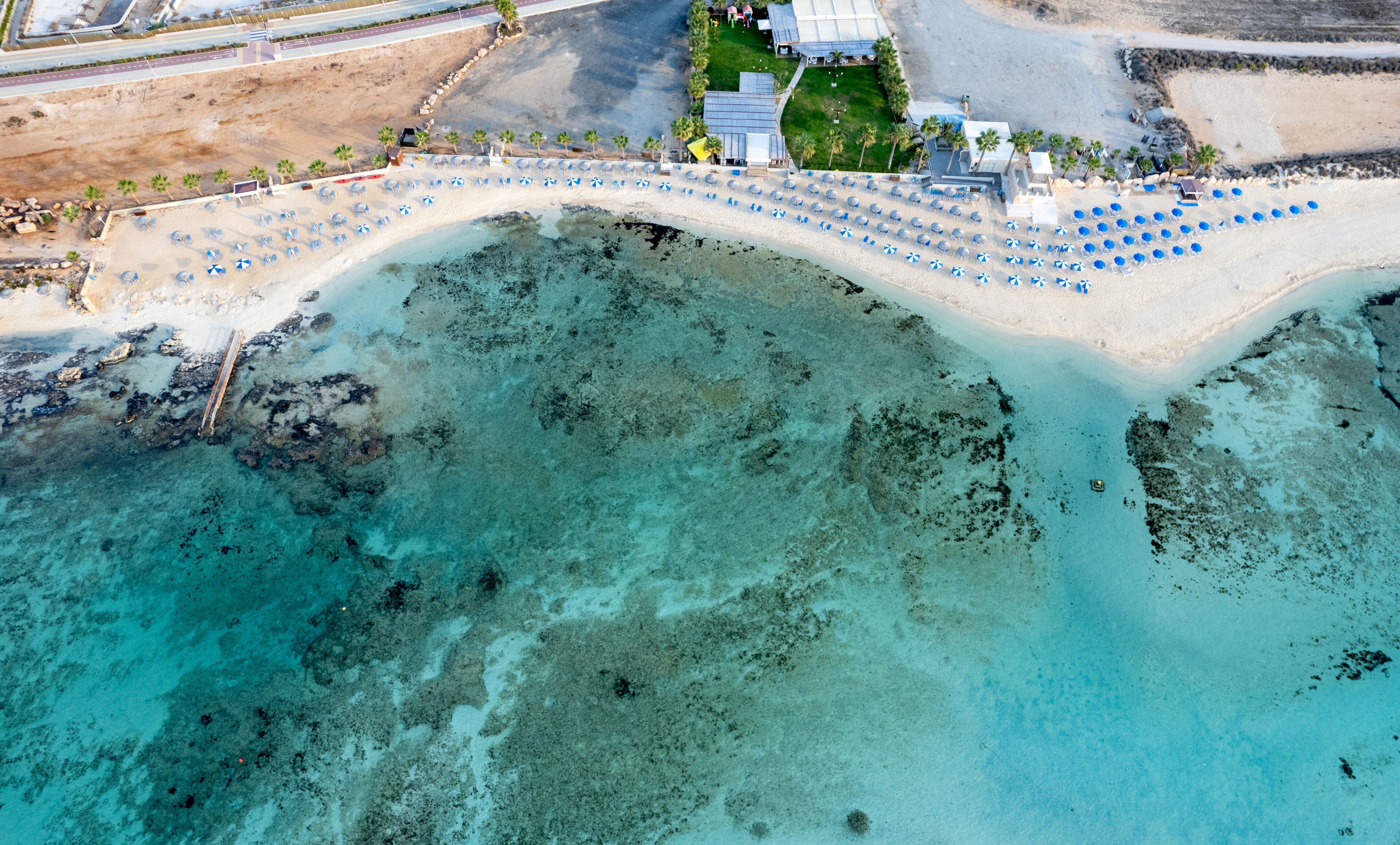 Drone aerial top view of a holiday resort and coastline with turquoise sea water.