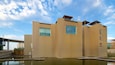 Ein modernes Gebäude mit Holzfassade und einem reflektierenden Wasserspiel davor.