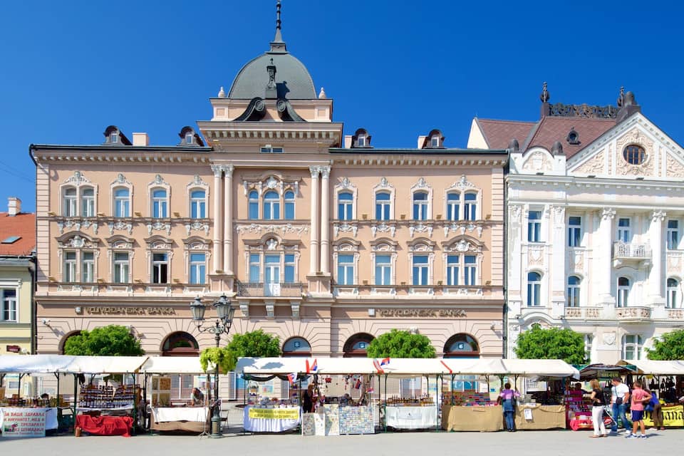 Un bâtiment historique à l’architecture riche et ornée, surmonté d’un dôme et entouré d’étals de marché.