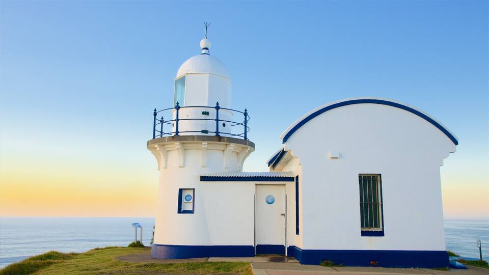 A lighthouse with a white and blue exterior, a small adjacent building, and a clear sky.