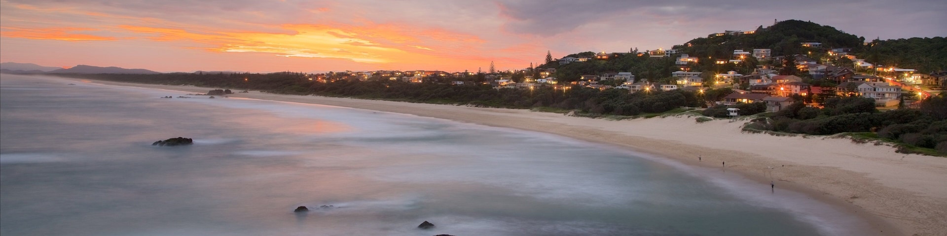 Port Macquarie caracterizando litoral rochoso, uma praia e um pôr do sol