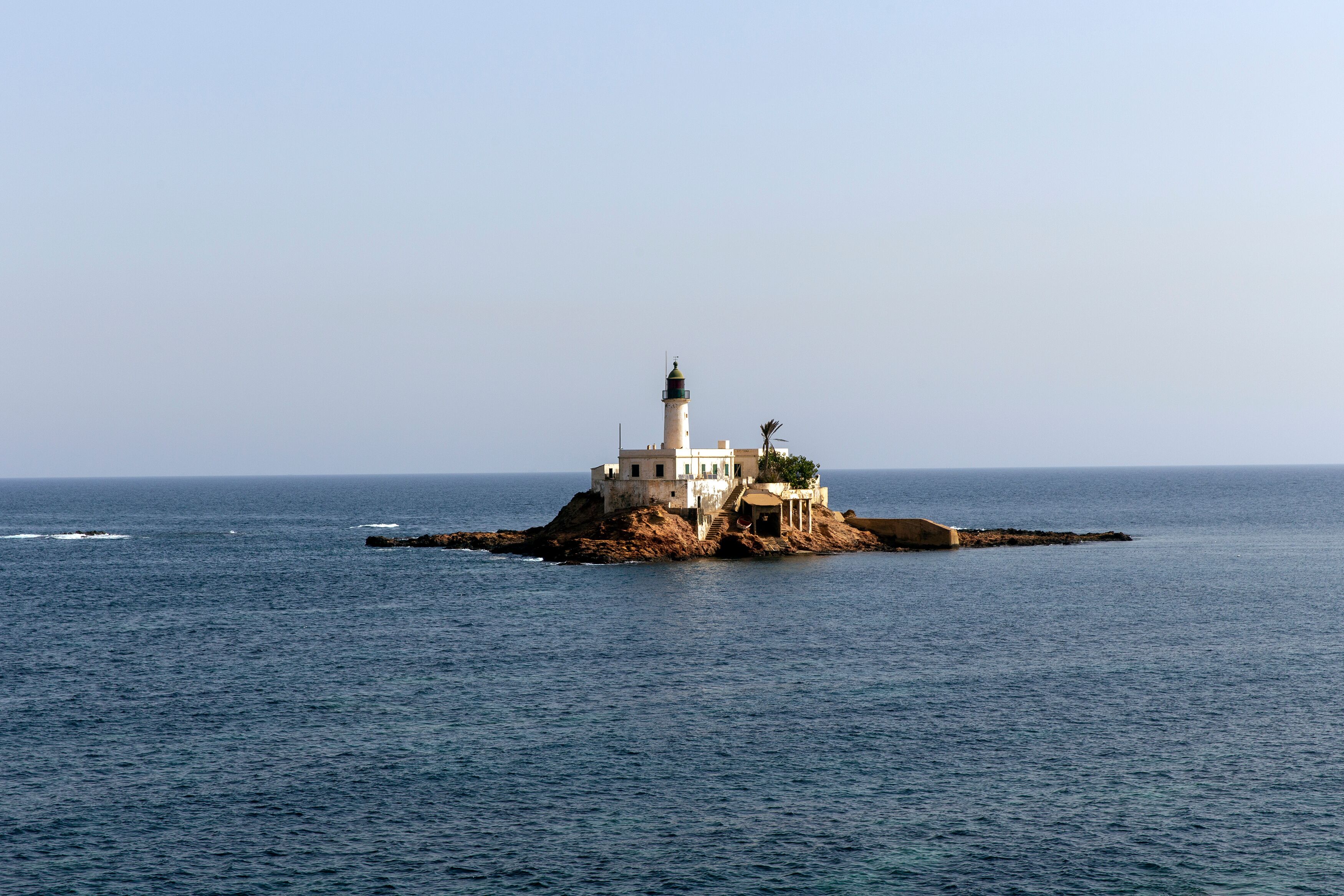 A lighthouse on a rocky island in the sea.