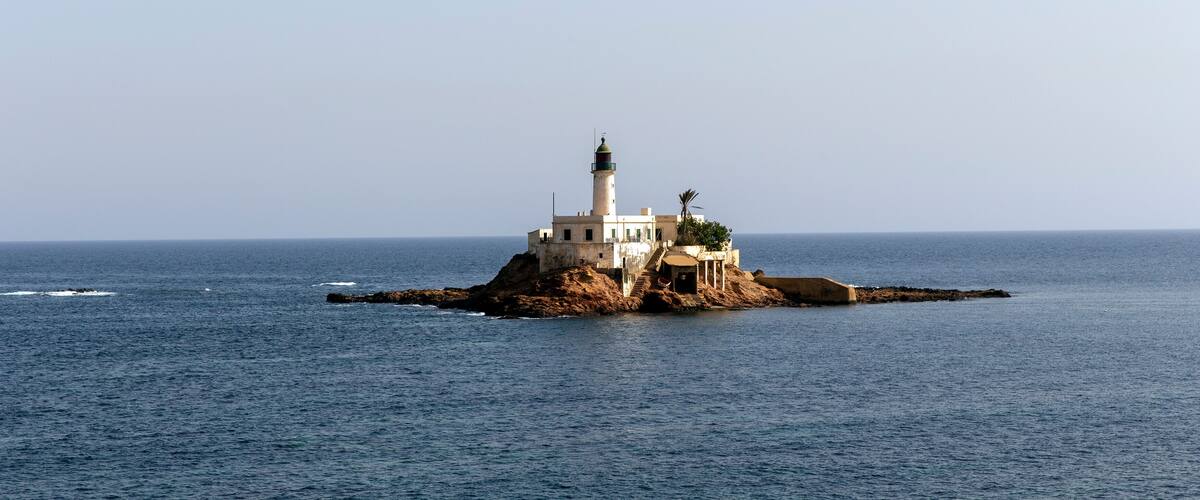 A lighthouse on a rocky island in the sea.