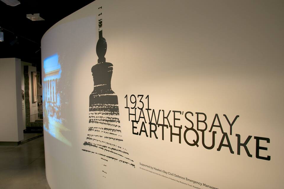 Een muur met de tekst '1931 HAWKESBAY EARTHQUAKE' en een projectie van een gebouw.