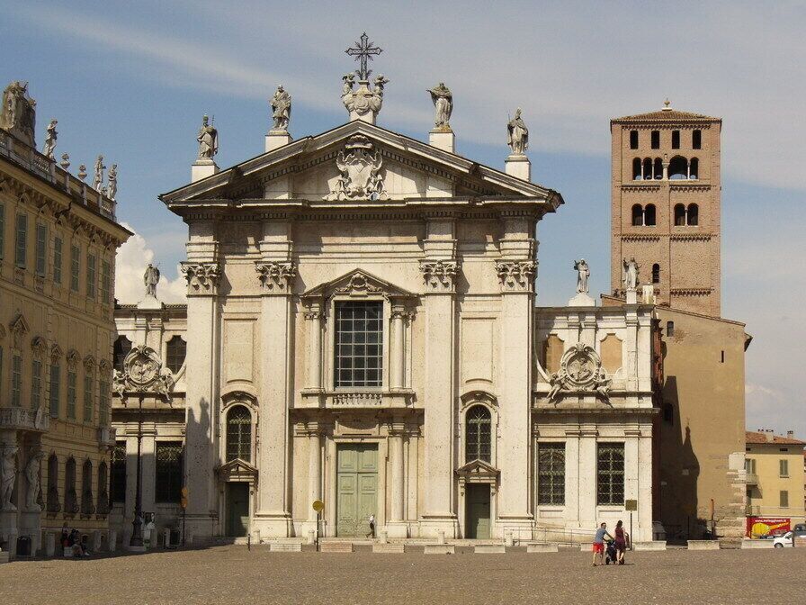 Un edificio histórico con arquitectura clásica, una torre de reloj destacada y un campanario al fondo.