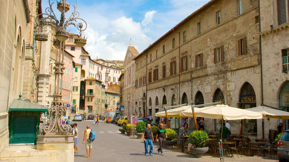 A historic street with ornate street lamps, a fountain, and outdoor cafes.