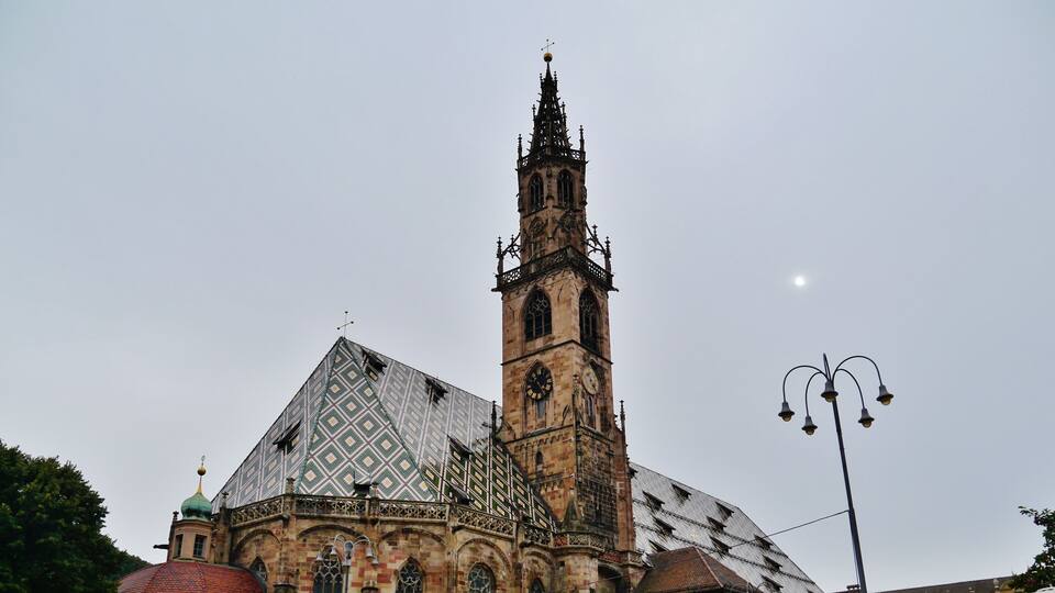 A historic church with a tall bell tower and patterned roof.